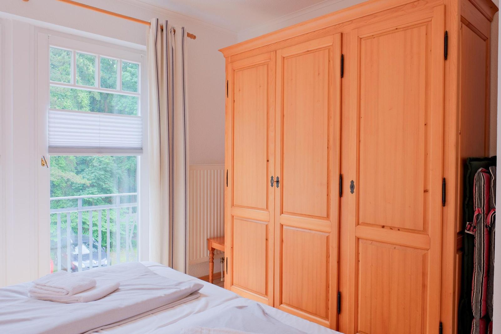 Schlafzimmer mit Holzschrank, Fenster und Bett