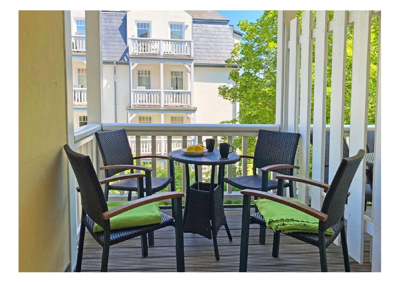 Terrasse mit Tisch und Stühlen, Blick auf Haus und Bäume.