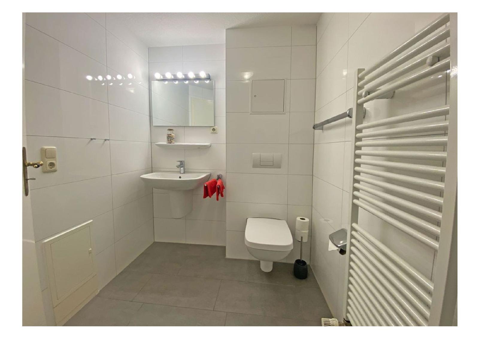 Badezimmer mit Toilette, Waschbecken und Heizkörper