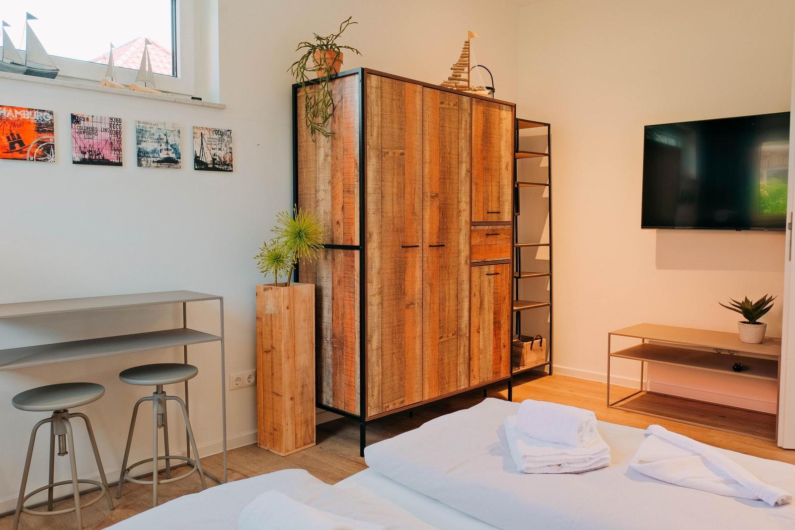 Schlafzimmer mit Bett, Kleiderschrank und Fernseher.