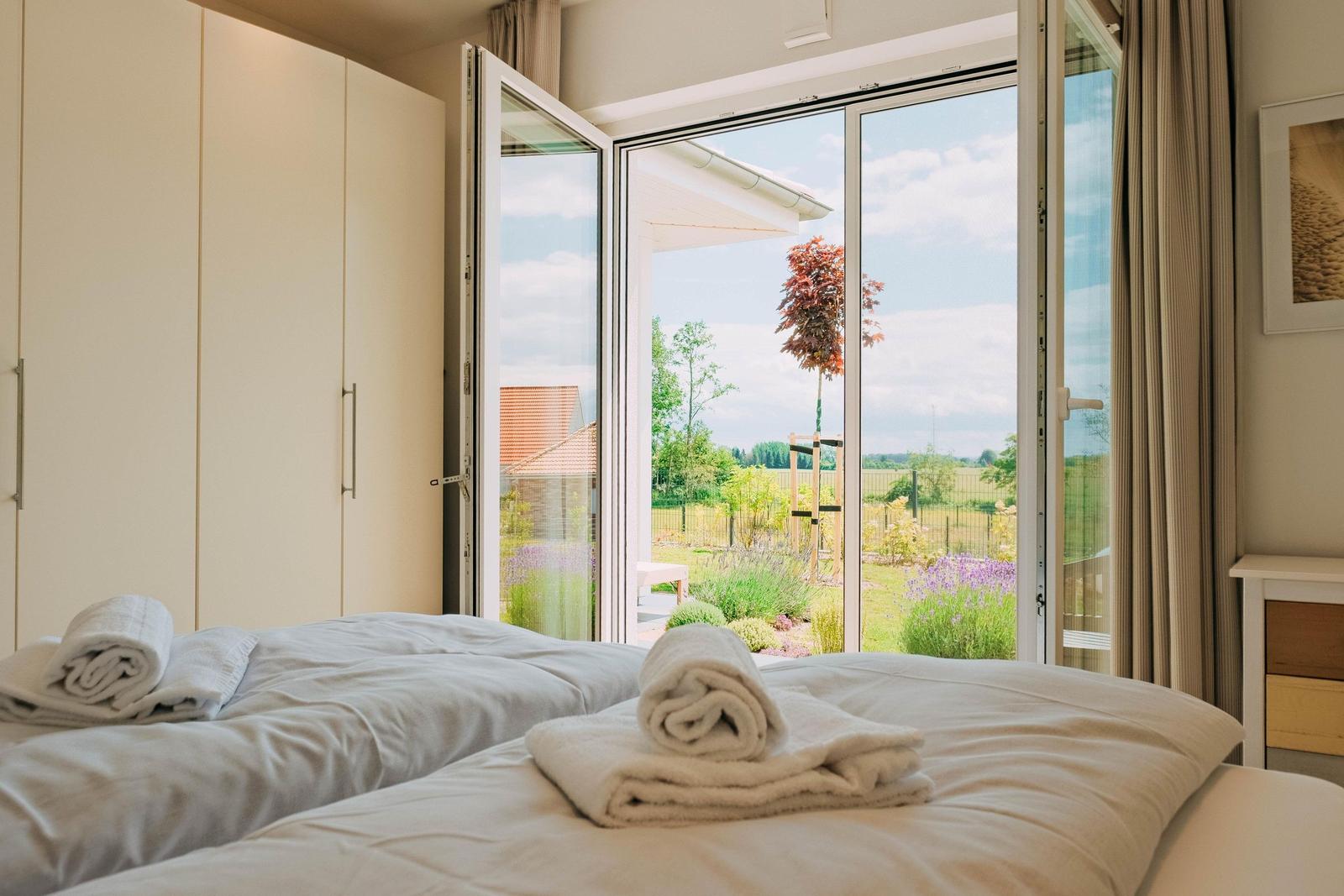 Schlafzimmer mit Blick auf Garten und Himmel durch Glastür