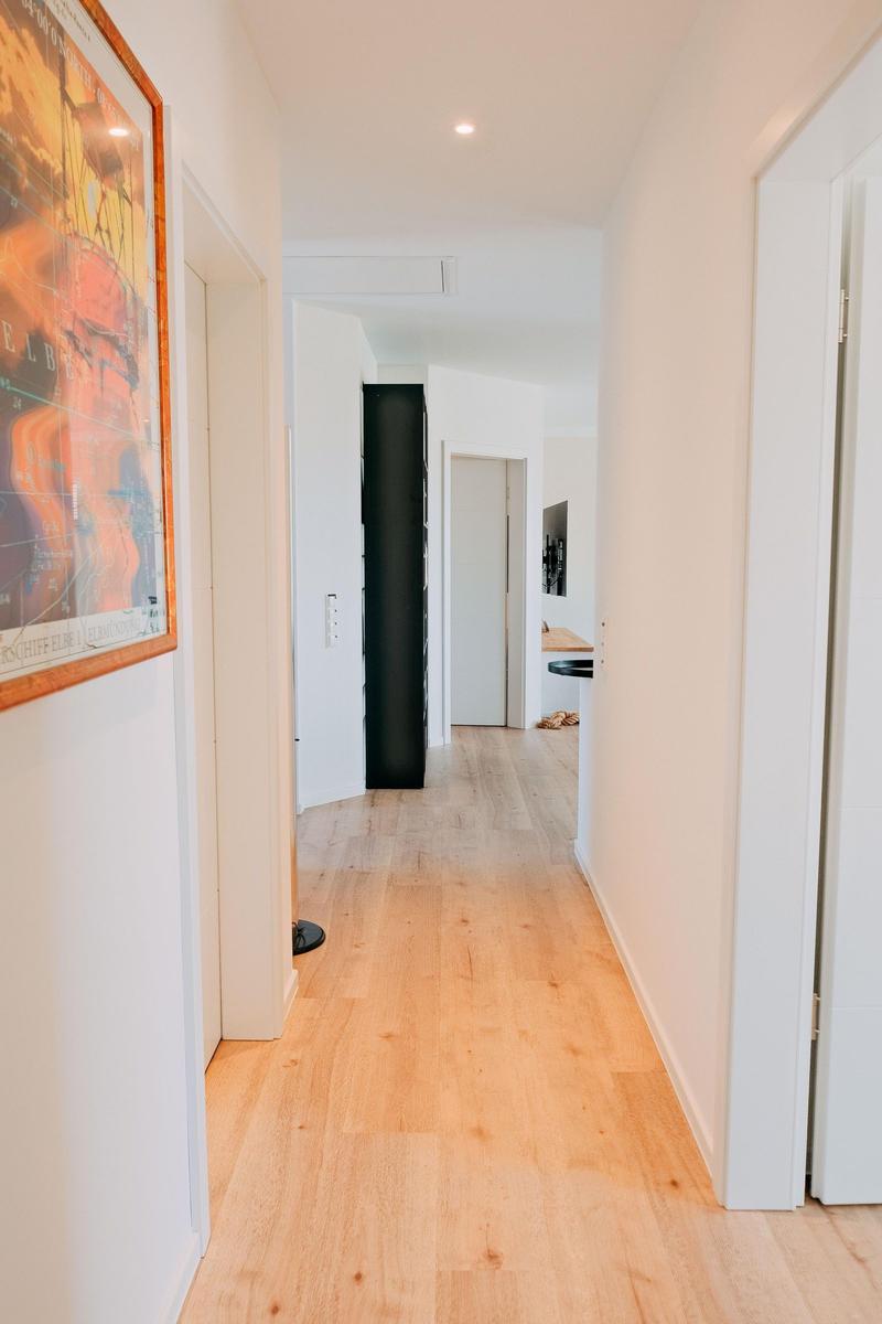 Flur mit Holzboden, Wandbild und Türen zu verschiedenen Räumen.
