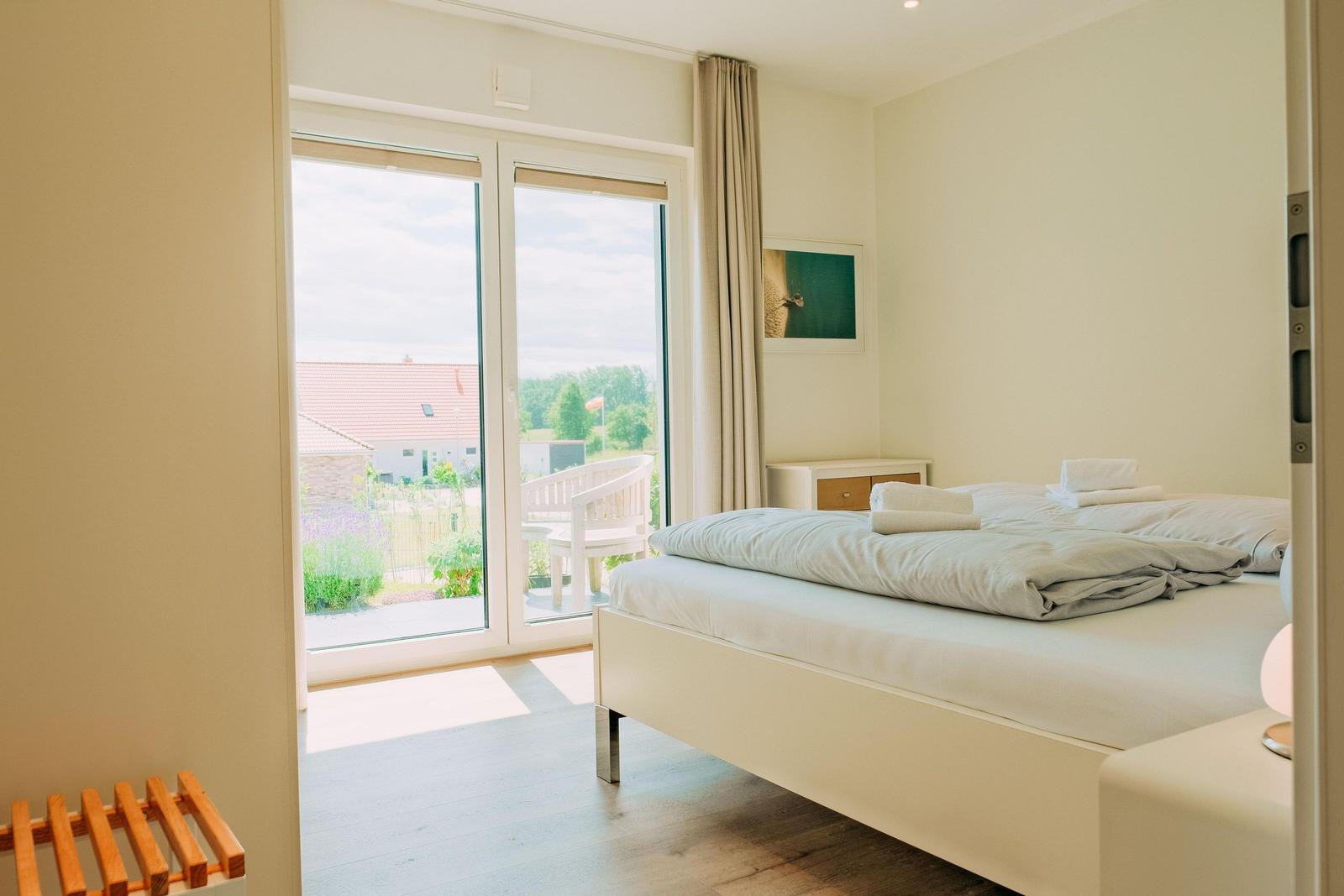 Schlafzimmer mit Bett, Balkon und Blick auf Garten