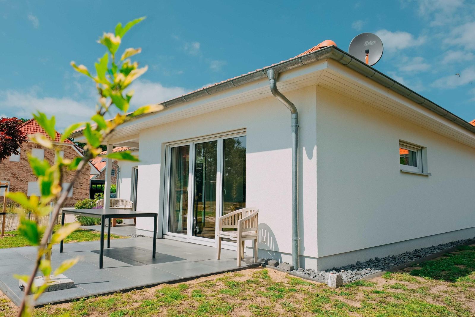 Moderne Villa mit Terrasse, Sitzgelegenheit und Satellitenanlage.