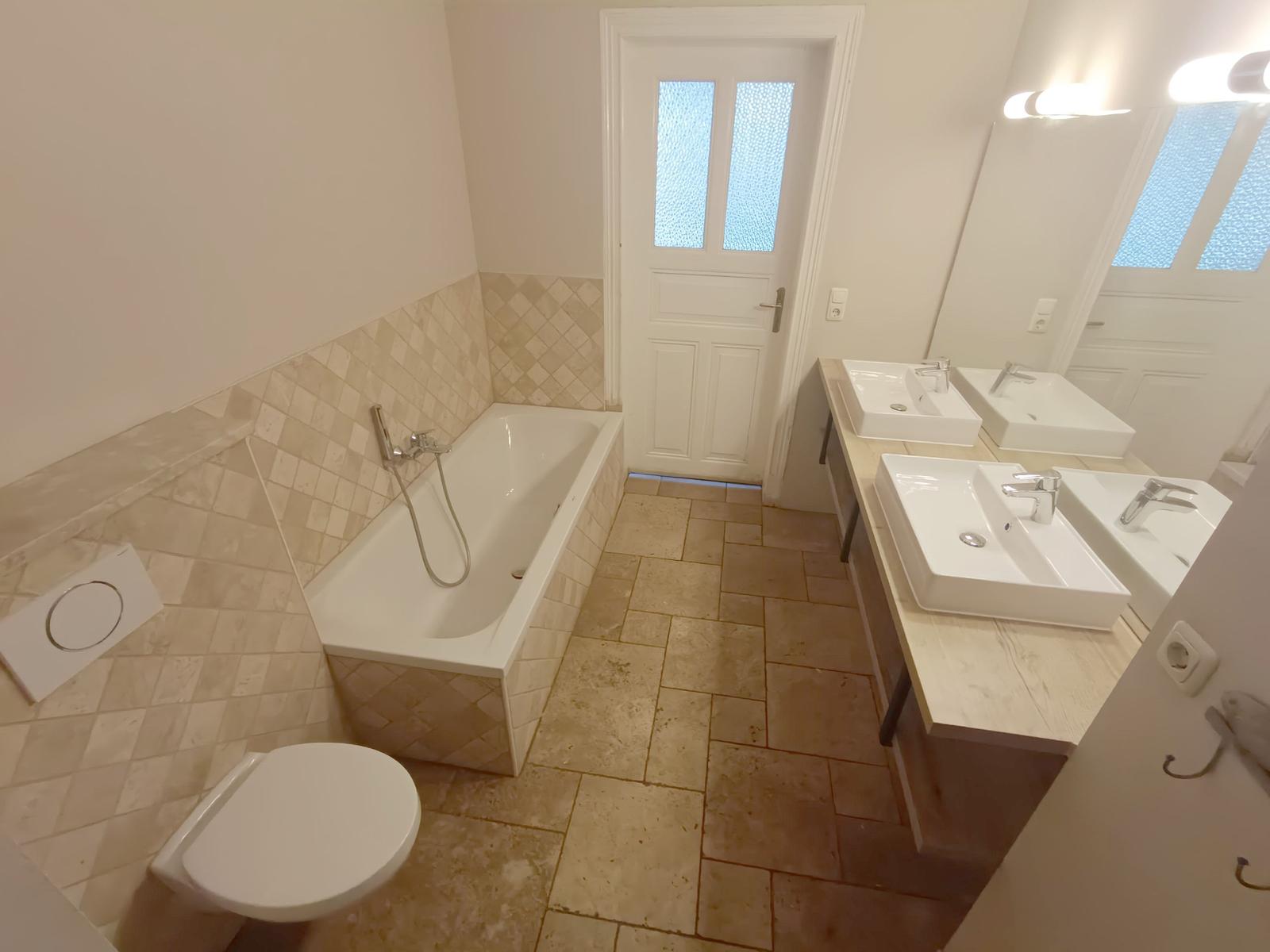 Bad mit Badewanne, Doppelwaschbecken und Toilette.