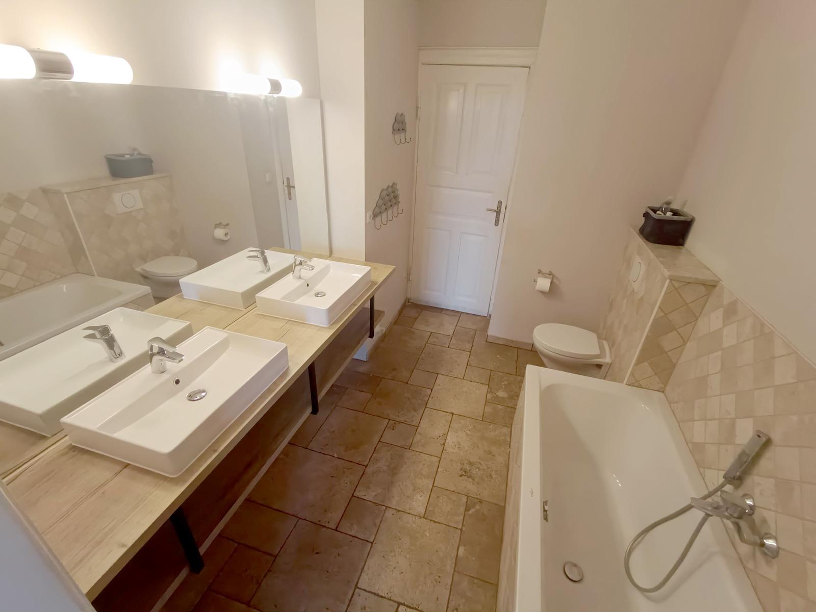 Badezimmer mit Dusche, Badewanne, zwei Waschbecken und Toilette.