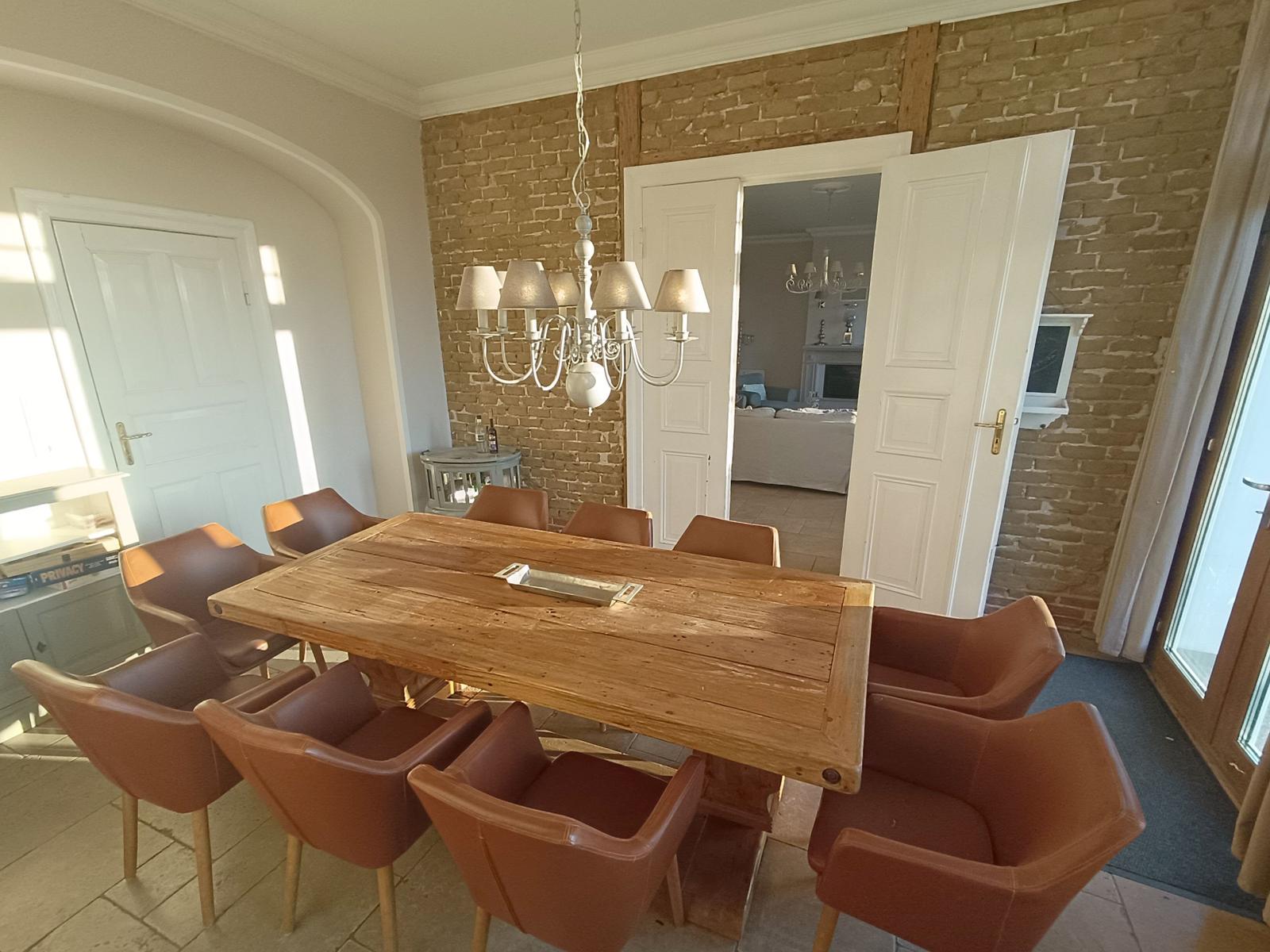 Esszimmer mit Holztisch, braunen Stühlen und Steinwand.