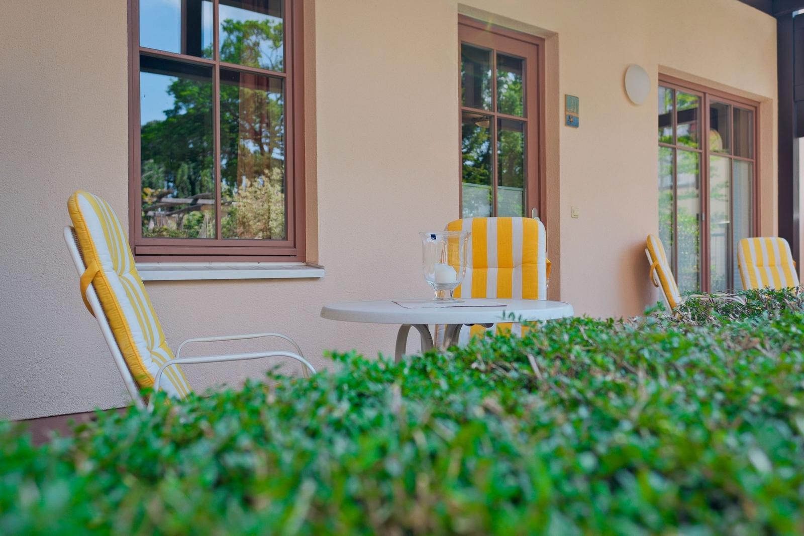 Terrasse mit Tisch und Stühlen mit gelb-weißen Kissen