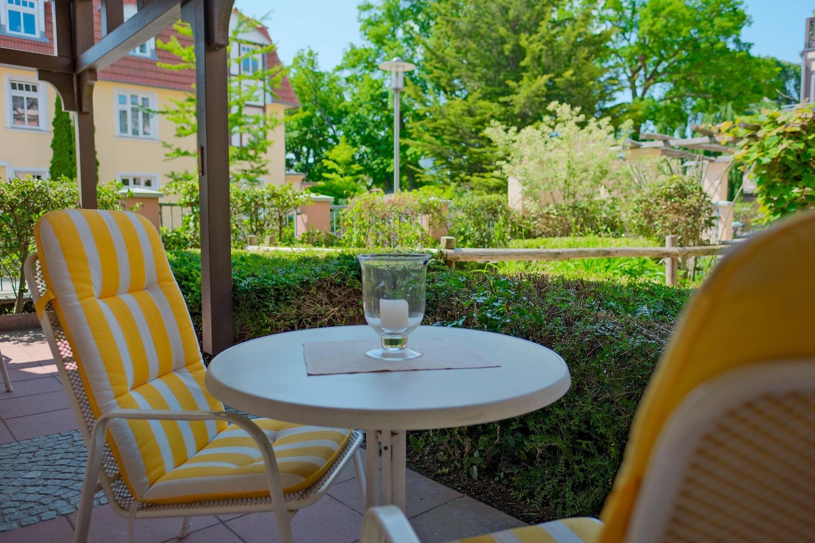 Terrasse mit Stuhl und Tisch, Blick auf grünen Garten und Häuser.