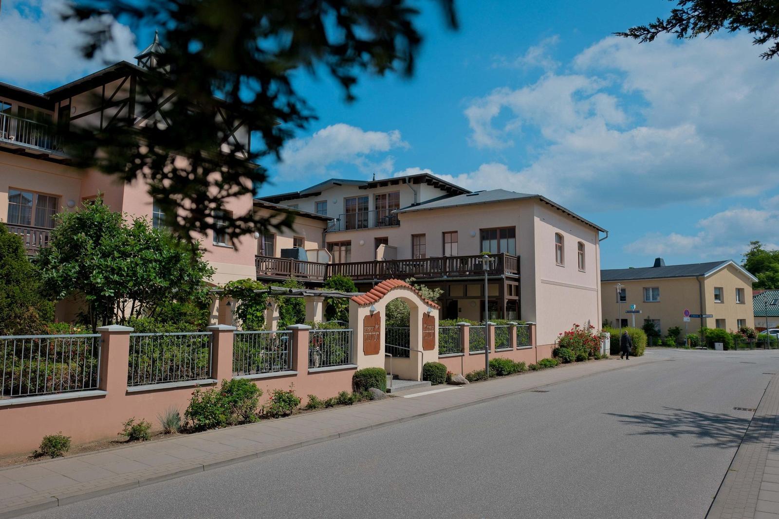 Ferienhaus mit Balkonen und Gartenzaun an Straße