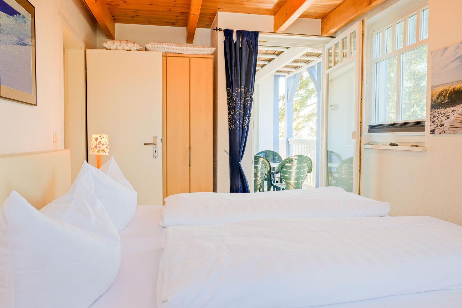 Schlafzimmer mit Doppelbett, Kleiderschrank und Blick auf Balkon.
