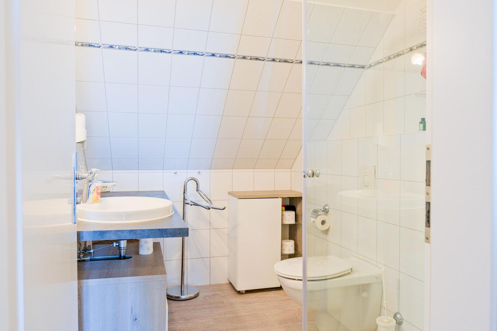 Badezimmer mit Dusche, Toilette und Waschbecken unter Dachschrägen.