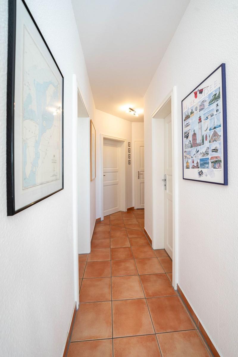 Flur mit Terrakottaboden und Wandbildern an den Wänden.