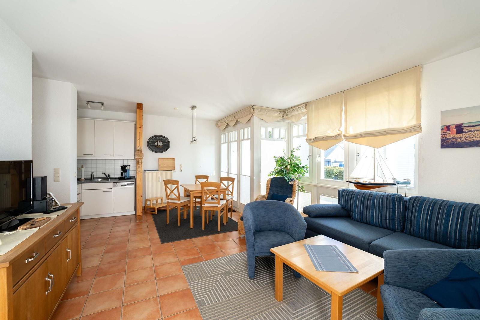 Wohnbereich mit Sofa, Esstisch und Küchenzeile. Fenster mit Blick aufs Meer.