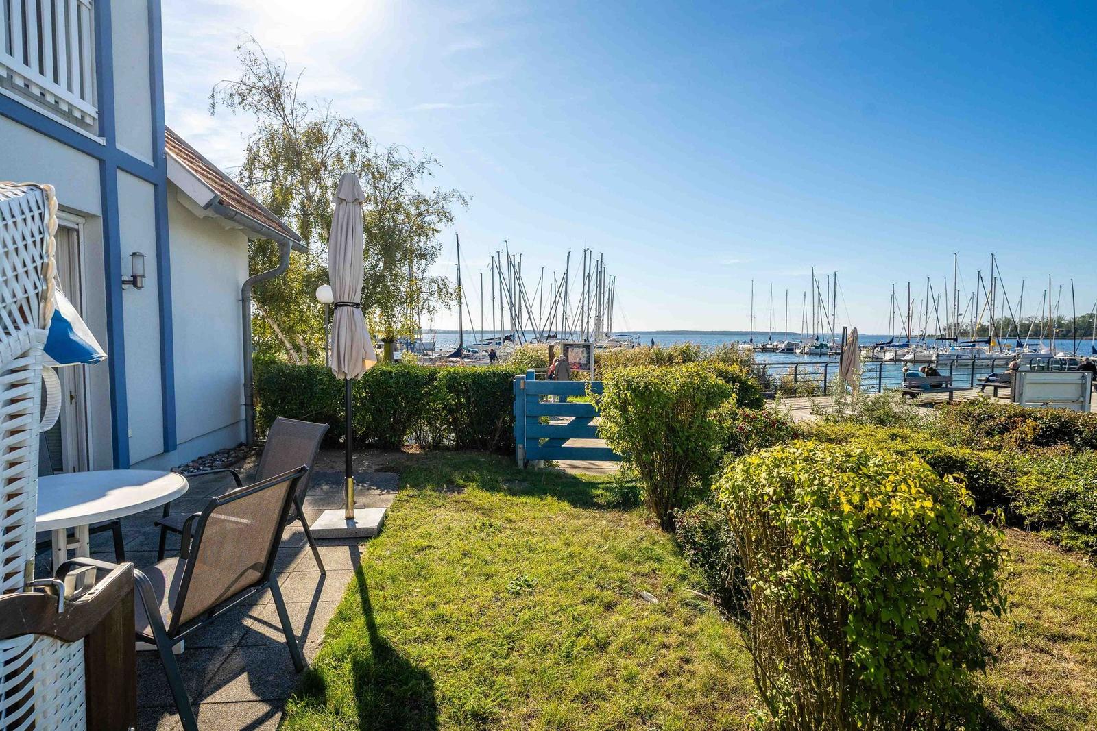 Terrasse mit Tisch und Stühlen, Blick auf Hafen mit Booten.