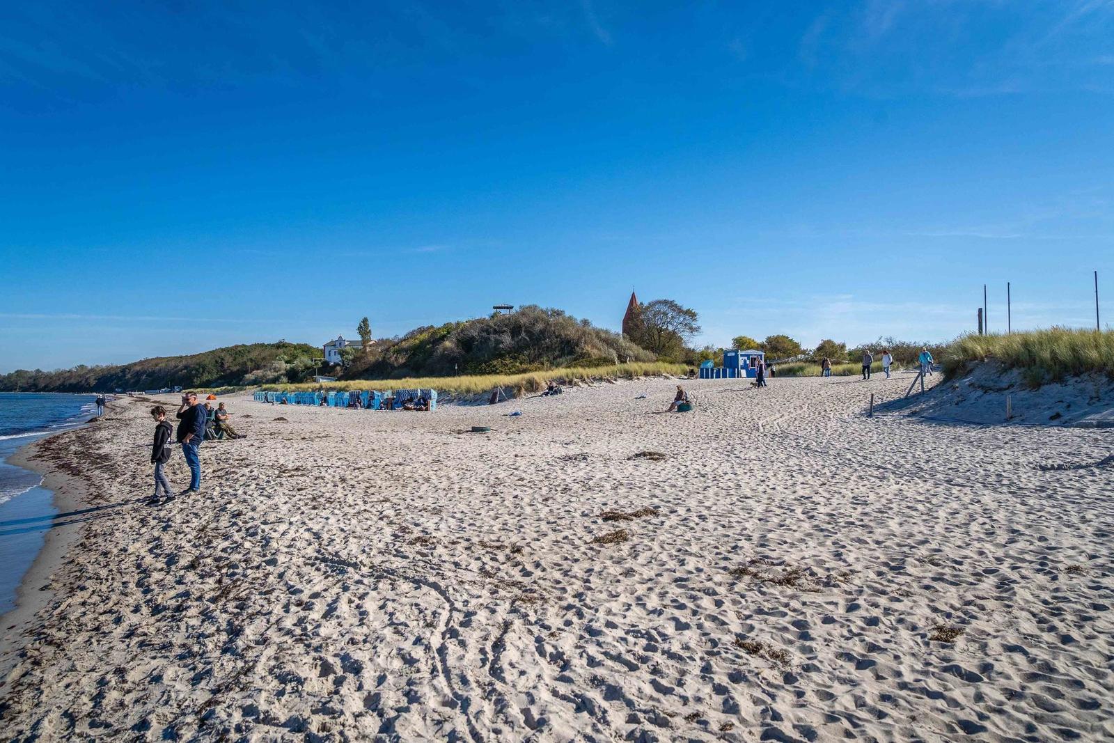 Strand mit Sand, Wellen und Menschen in der Ferne