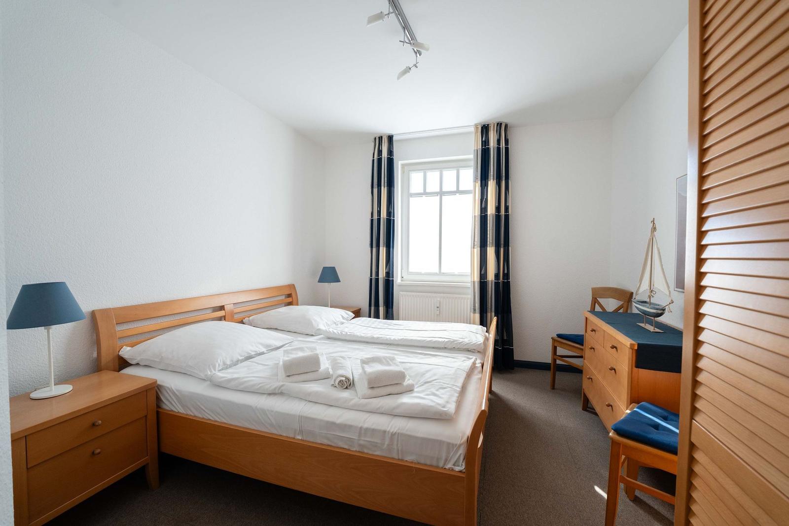 Ein Schlafzimmer mit einem Doppelbett, einem Schreibtisch und einem Fenster.