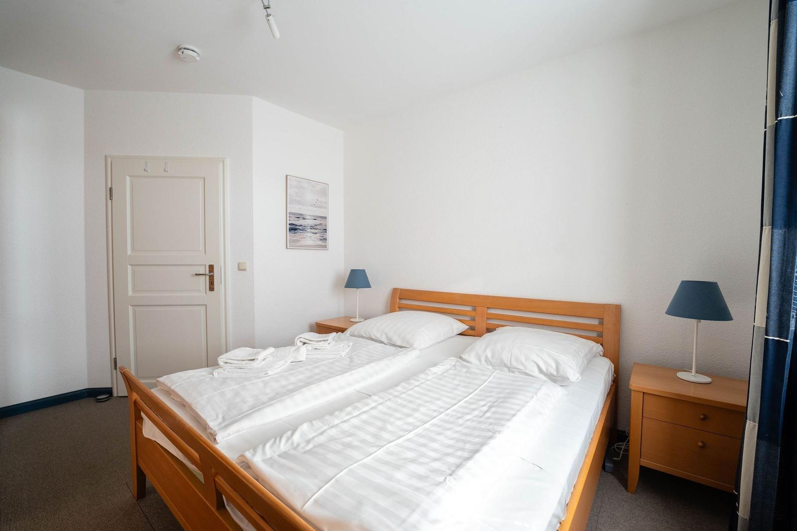 Schlafzimmer mit Doppelbett, zwei Nachttischen und einer Tür.