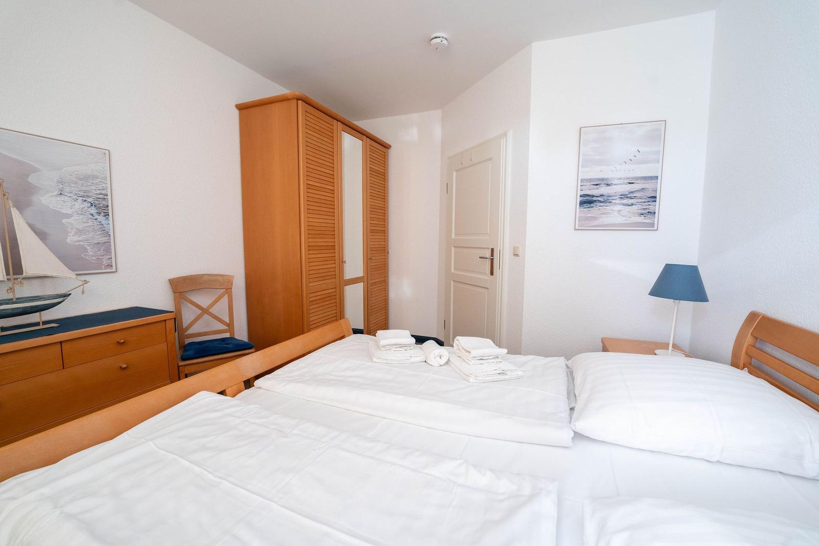 Schlafzimmer mit Doppelbett, Kleiderschrank und Bildern an den Wänden.