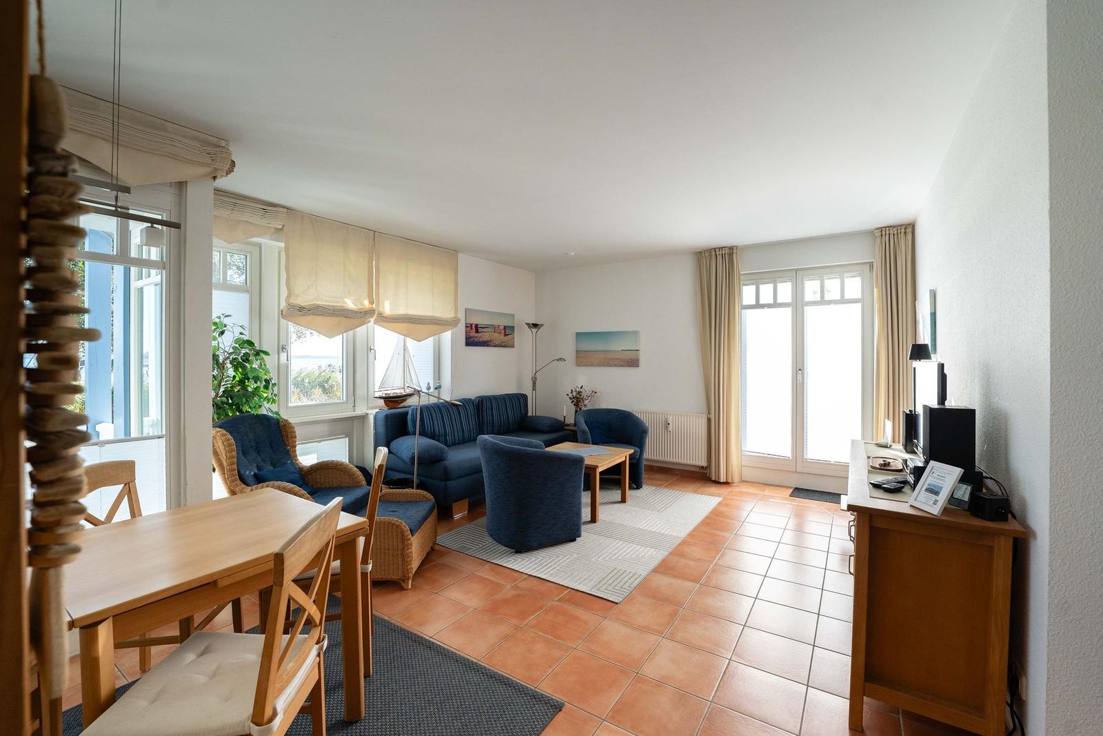 Wohn- und Essbereich mit Sofa, Stühlen und Fenstern.