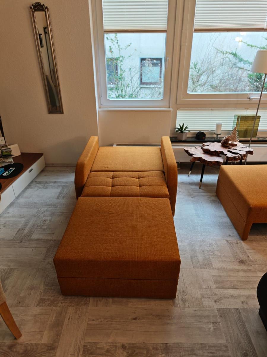 Orange Sofa und Sitzbank im Wohnzimmer mit Holzboden und Fenster.