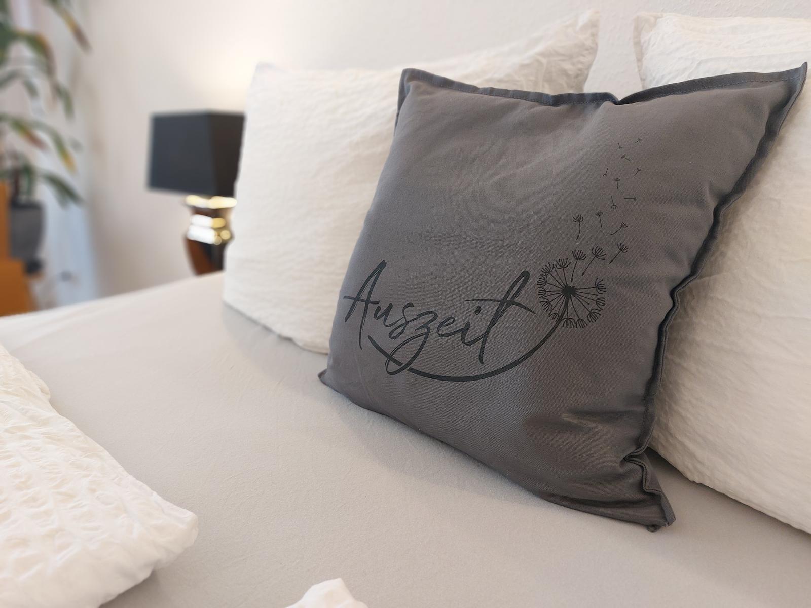 Bettkopfteil mit Kissen und dekorativer Kissen mit Aufschrift.