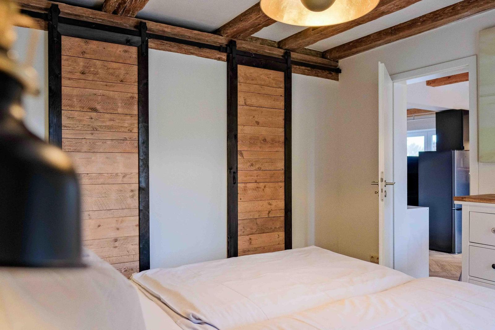 Schlafzimmer mit Holzpaneelen und Bett. Durchgang zur Küche sichtbar.