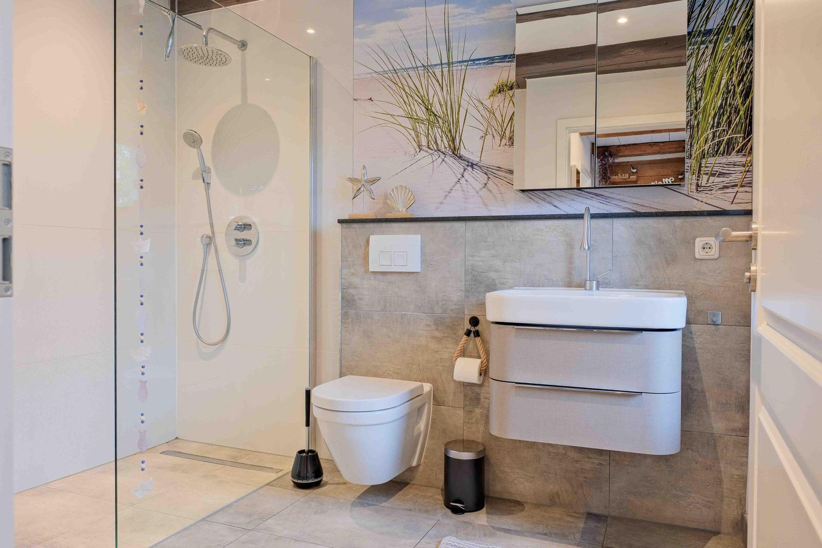 Dusche mit Glaswand, Waschbecken und Toilette in moderner Badezimmerausstattung.