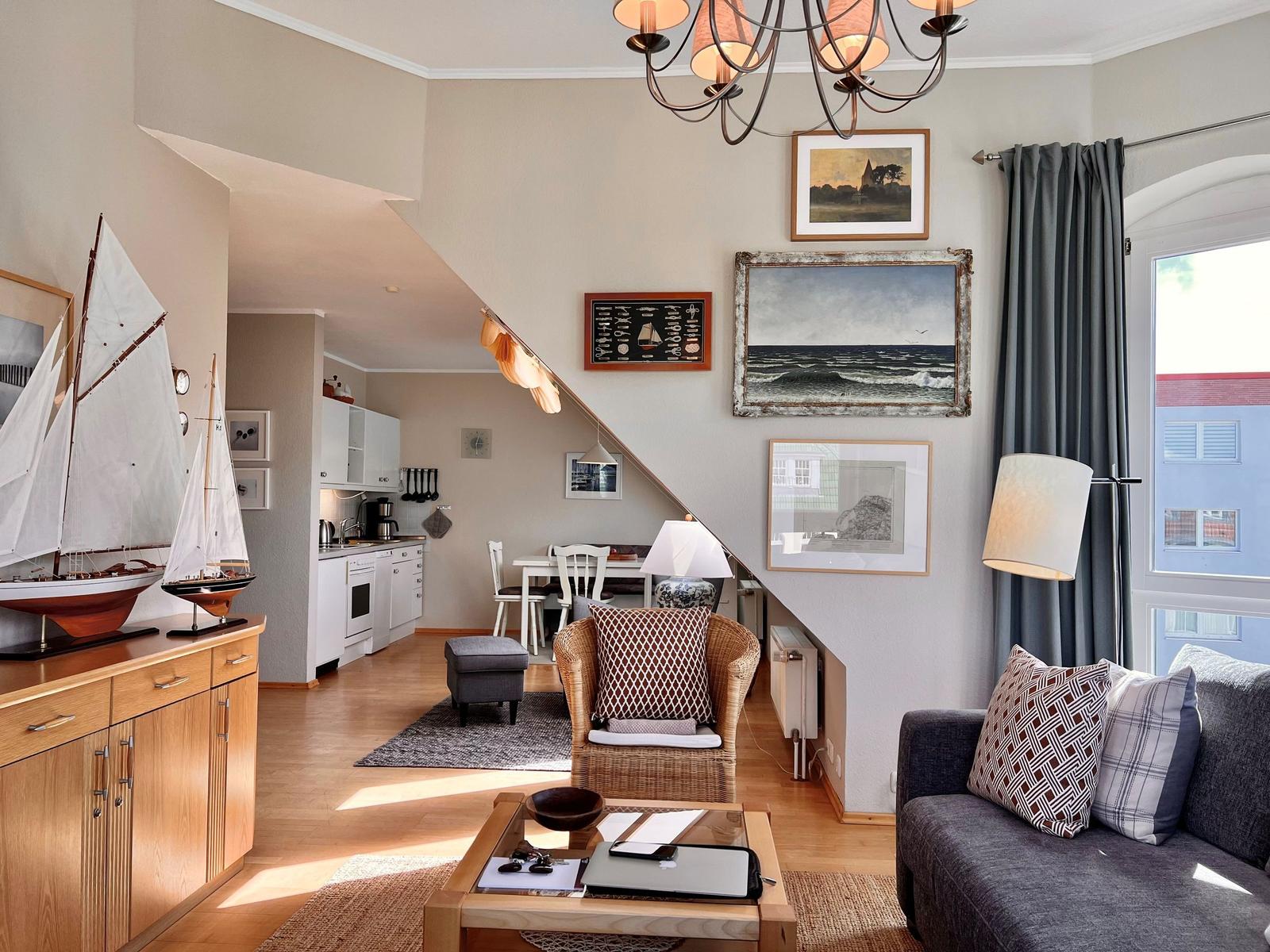 Wohnzimmer mit Sofa, Sessel und Küchenbereich unter Treppe