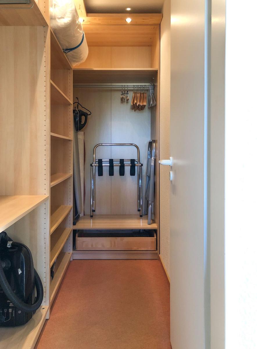 Ein Kleiderschrank mit Regalen, Kleiderständer und einem Rollator.