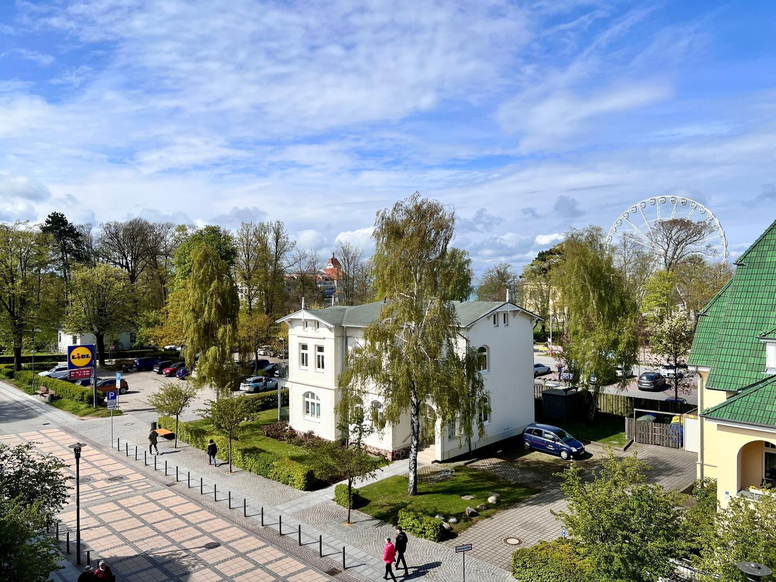 Weißes Haus mit Garten, Parkplatz und Blick auf Riesenrad.