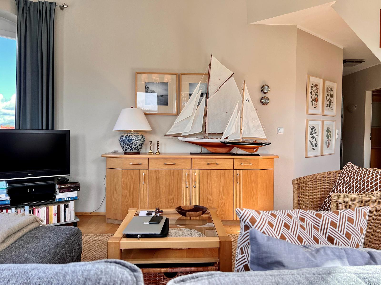 Wohnzimmer mit Holzmöbeln, Segelschiffmodell und Fernseher.