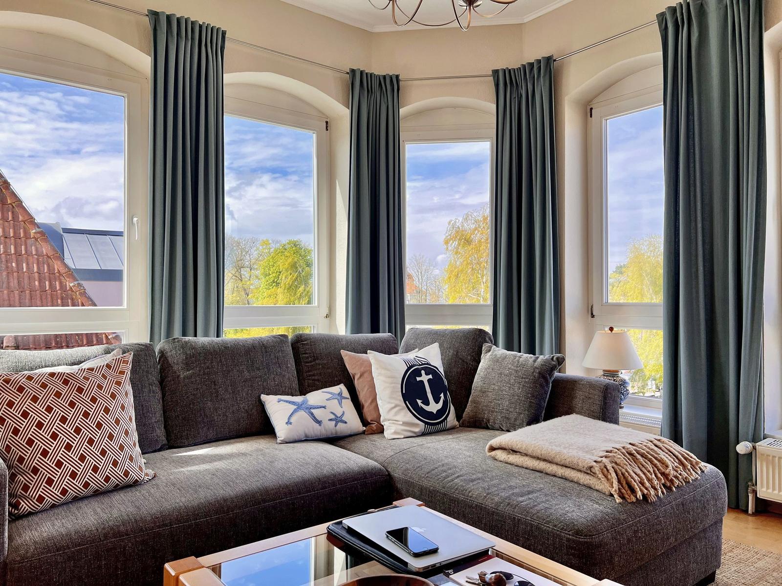 Wohnzimmer mit Sofa, Kissen und Blick auf Außen