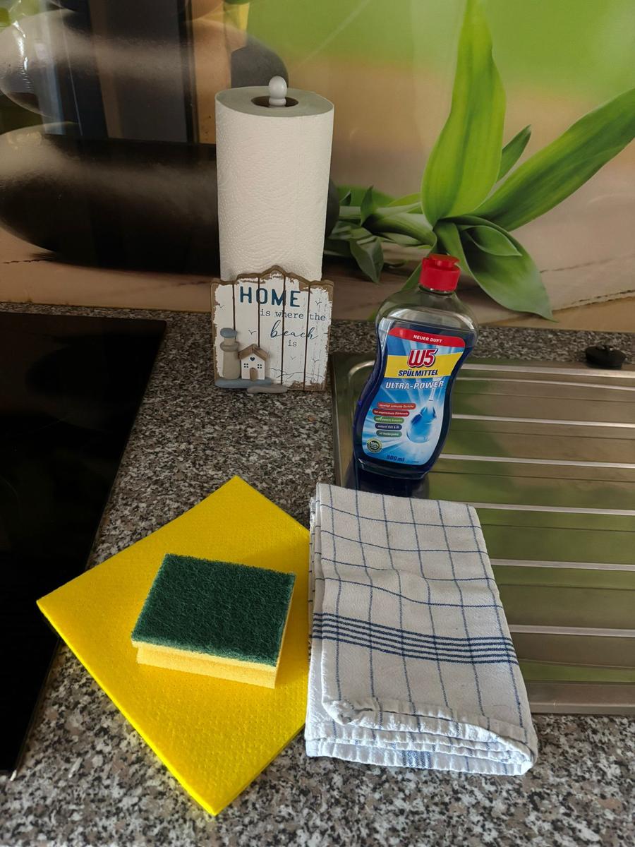 Küchenarbeitsfläche mit Reinigungsmitteln und Küchenhandtüchern.