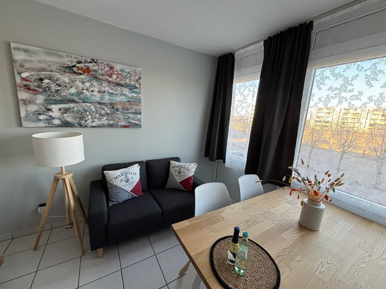 Wohn- und Essbereich mit Sofa, Tisch und Fenster.