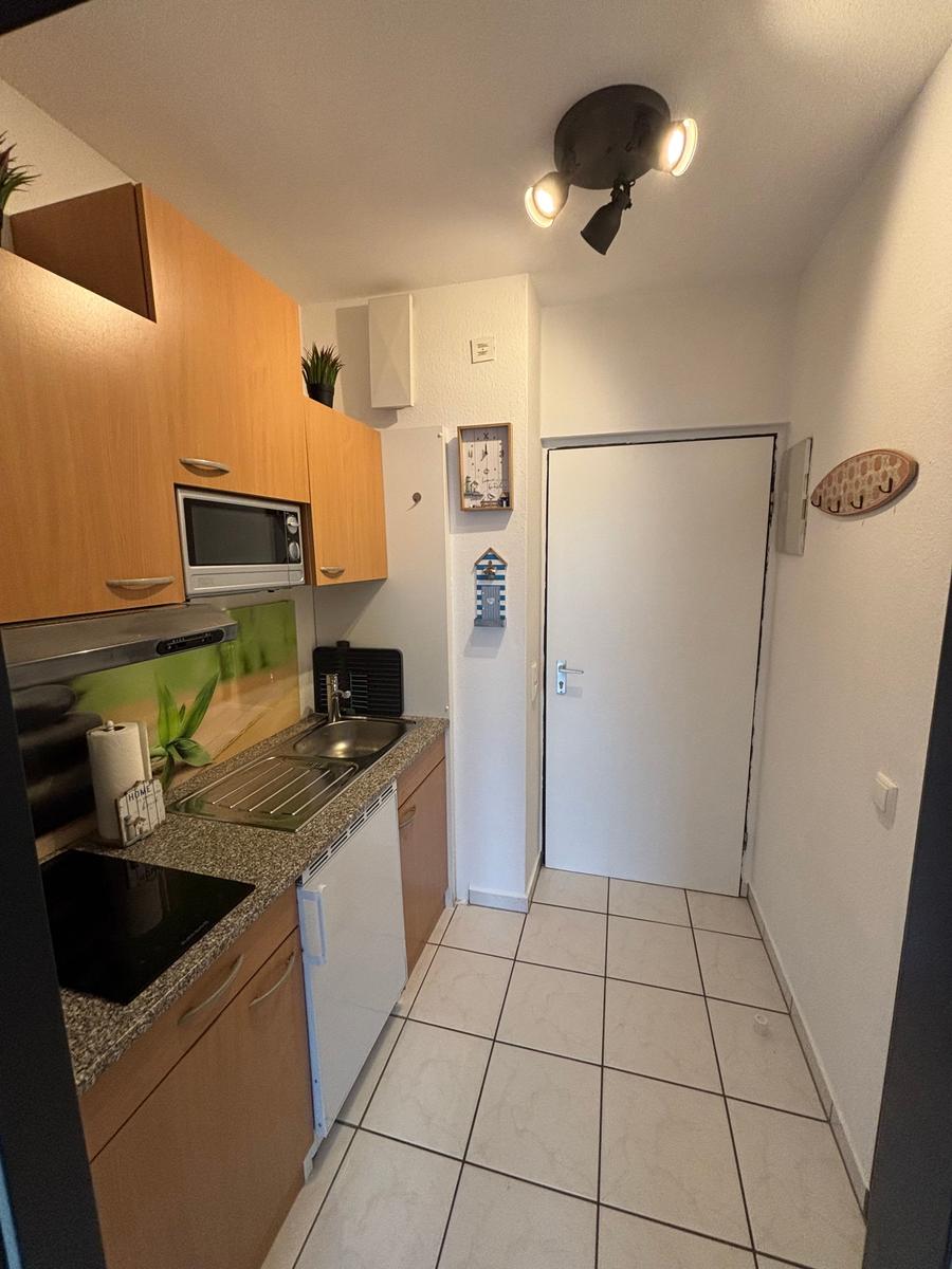 Küche mit Holzschrank, Spüle und Kochfeld.