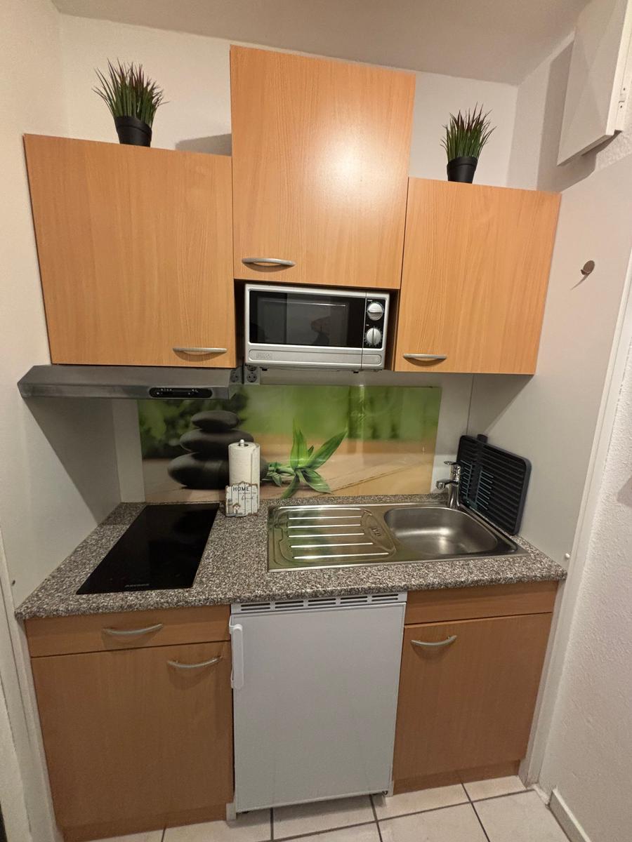 Küche mit Holzschränken, Mikrowelle, Spüle und Kühlschrank.