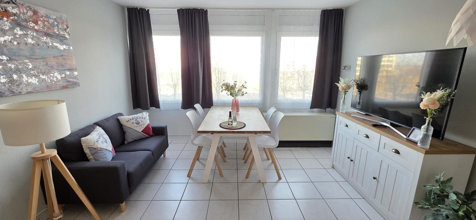 Wohn- und Essbereich mit Sofa, Esstisch und Fernseher.