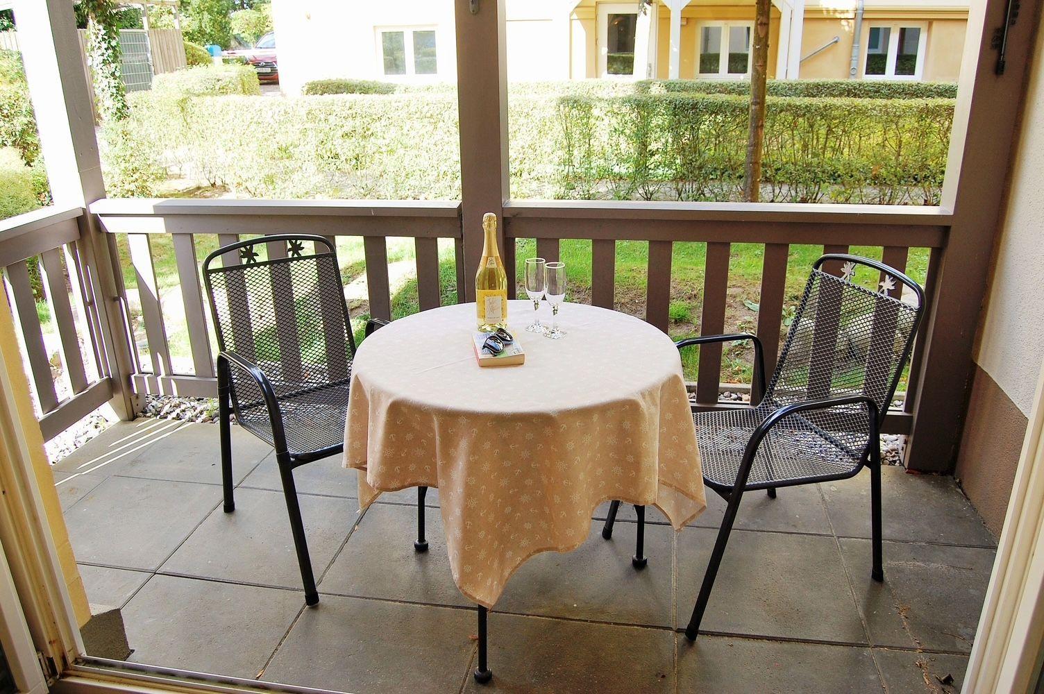 Terrasse mit runden Tisch, zwei Stühlen und Flasche Champagner.