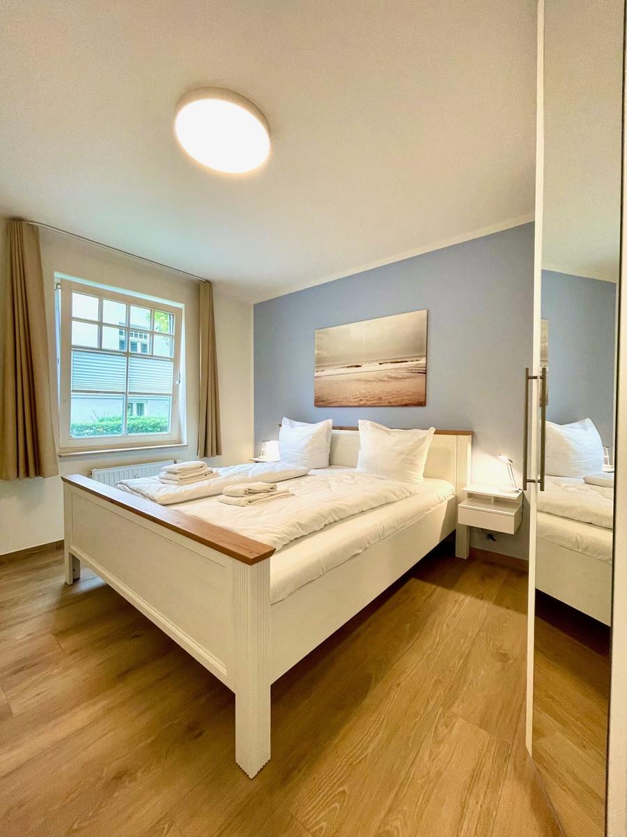 Schlafzimmer mit Bett, Fenster und Wandbild.