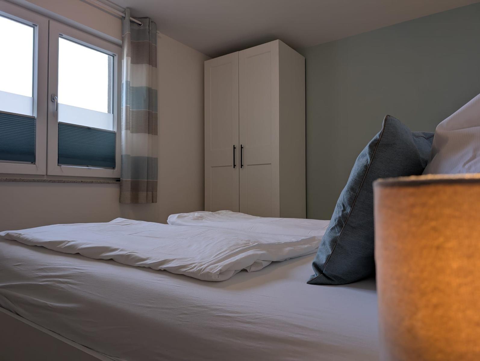 Schlafzimmer mit Bett, Kleiderschrank und Fenster mit Vorhängen.