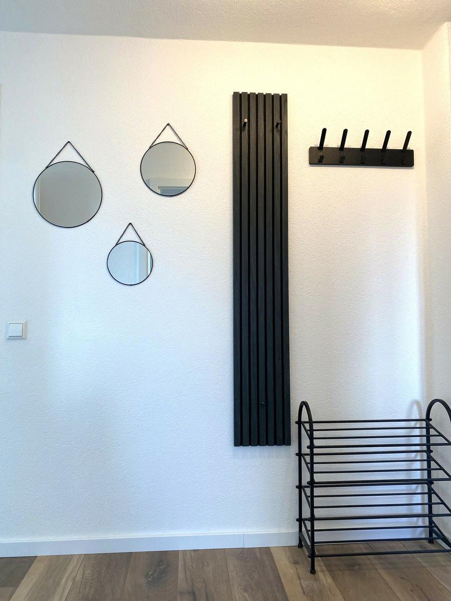 Wand mit drei runden Spiegeln, Heizkörper und Garderobe