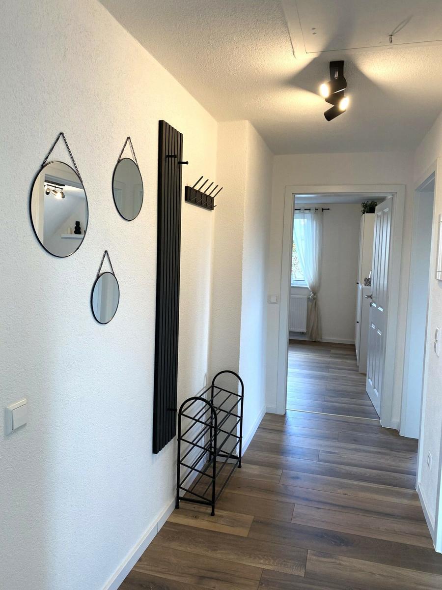 Flur mit drei runden Spiegeln, Heizkörper und Holzboden