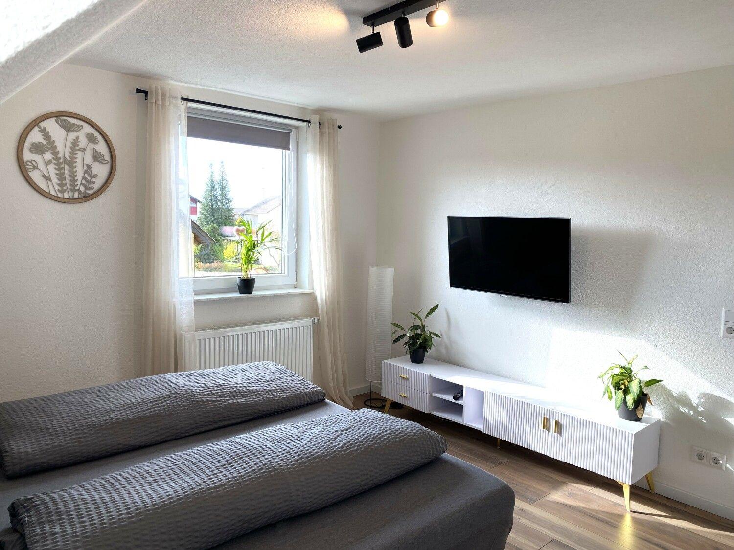 Schlafzimmer mit Bett, Fernseher und Fenster mit Blick.