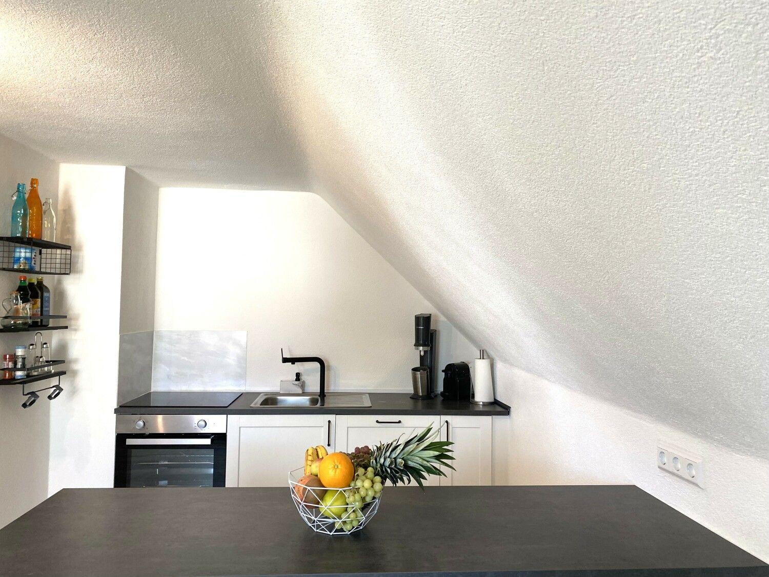 Küche mit Schranksystem, Spüle und Kochfeld unter schrägem Dach