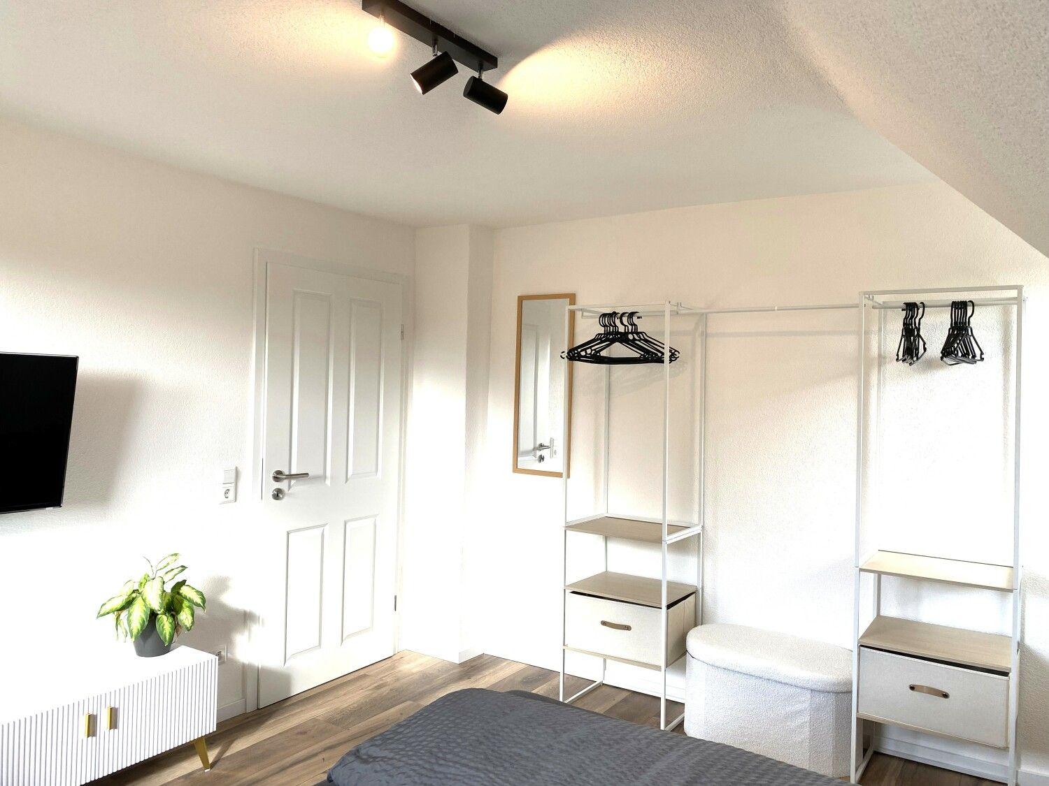 Schlafzimmer mit Bett, Kleiderschränken, Fernseher und Pflanze.