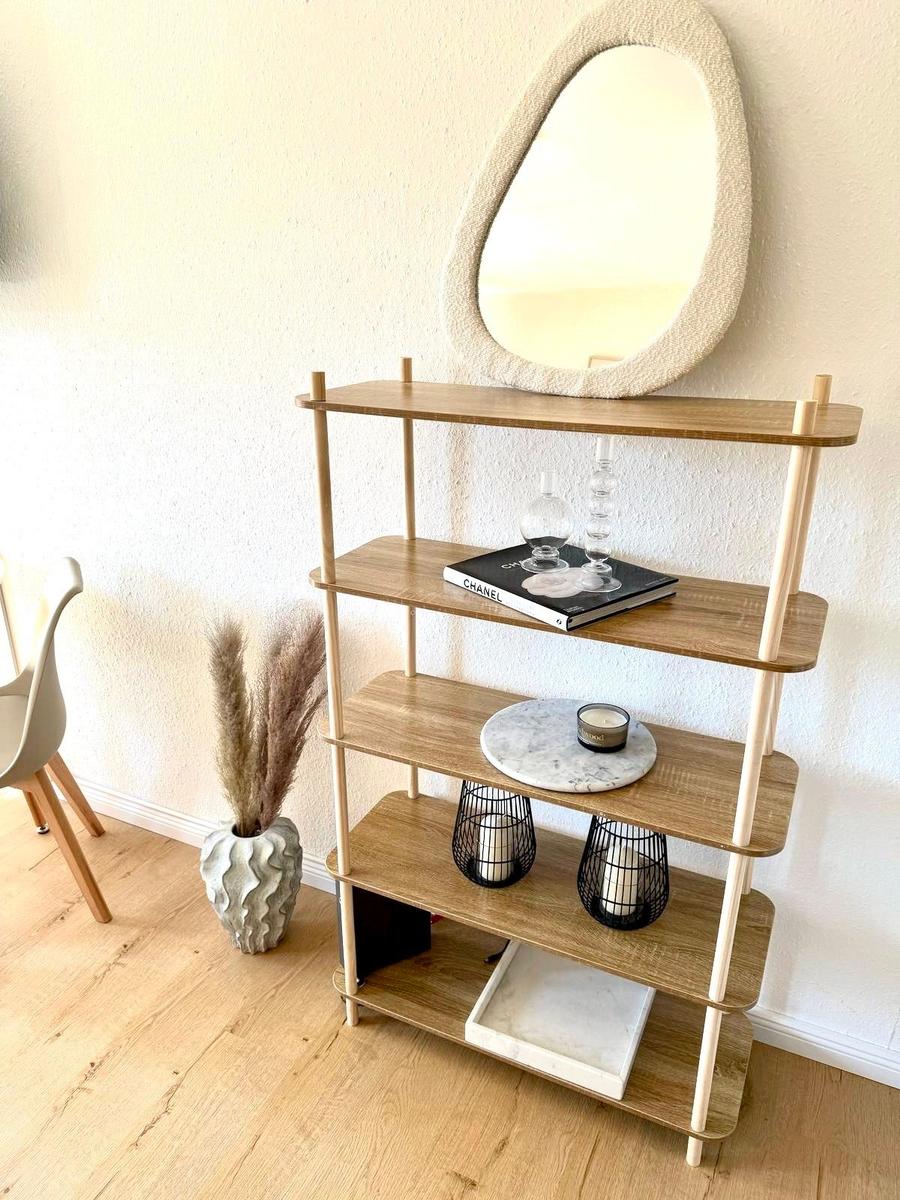 Hocker mit vier Ebenen, Spiegel darüber, Pflanze daneben.