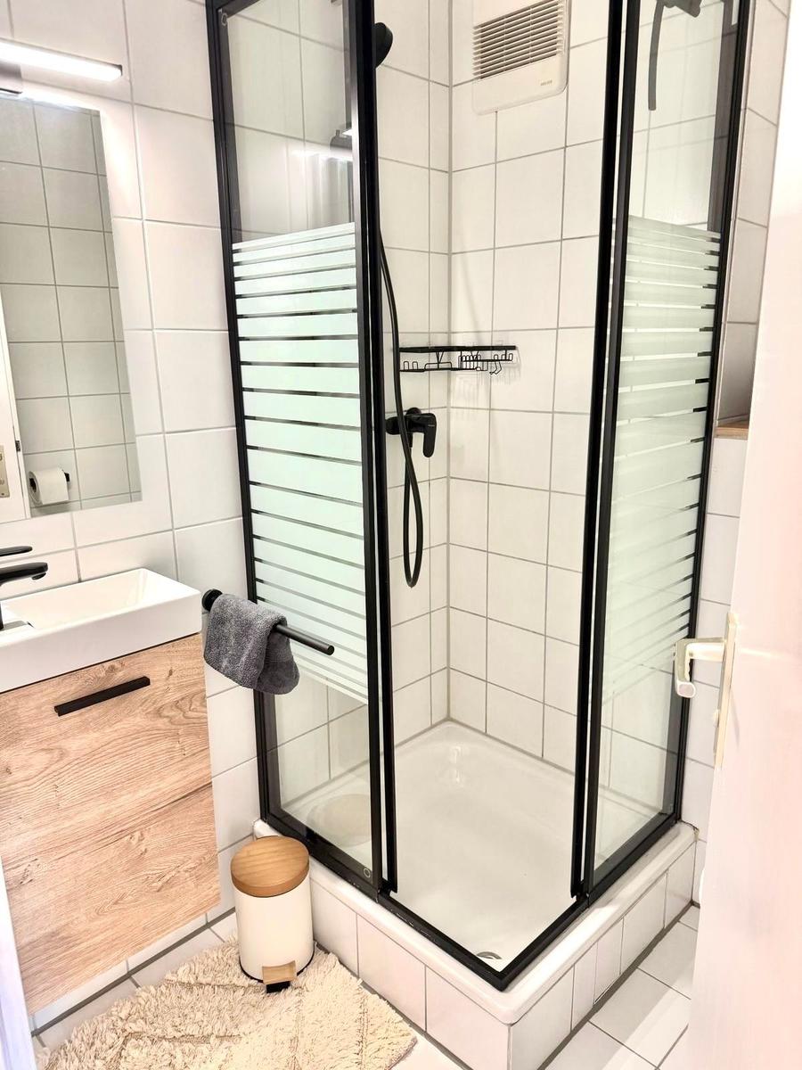 Badezimmer mit Duschkabine, Waschbecken und Spiegel.