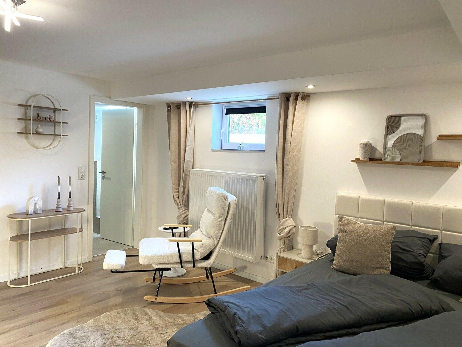 Schlafzimmer mit Bett, Schaukelstuhl und Fenster