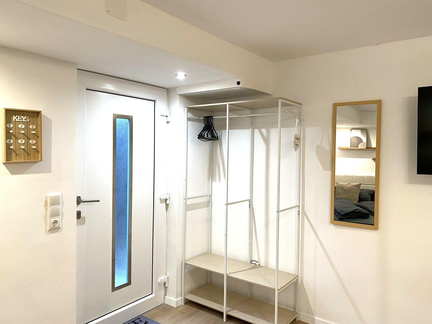 Eingangsbereich mit Schrank, Spiegel und Tür mit blauem Glas.